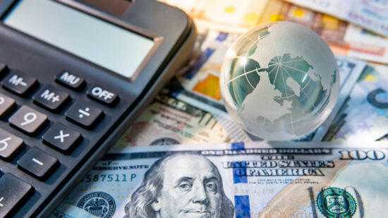 Global business and economy. World globe crystal glass and calculator on various international money banknotes. Currency exchange rate. Financial investment concept