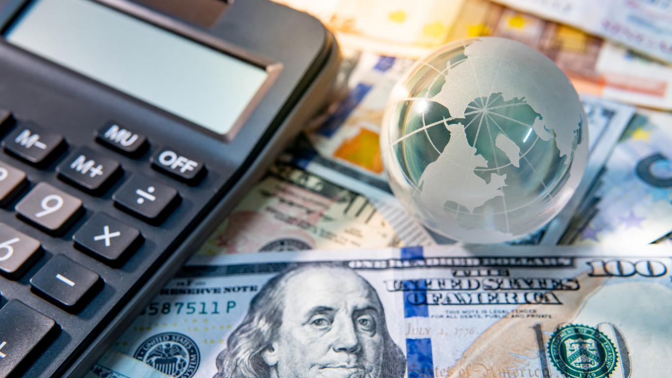 Global business and economy. World globe crystal glass and calculator on various international money banknotes. Currency exchange rate. Financial investment concept